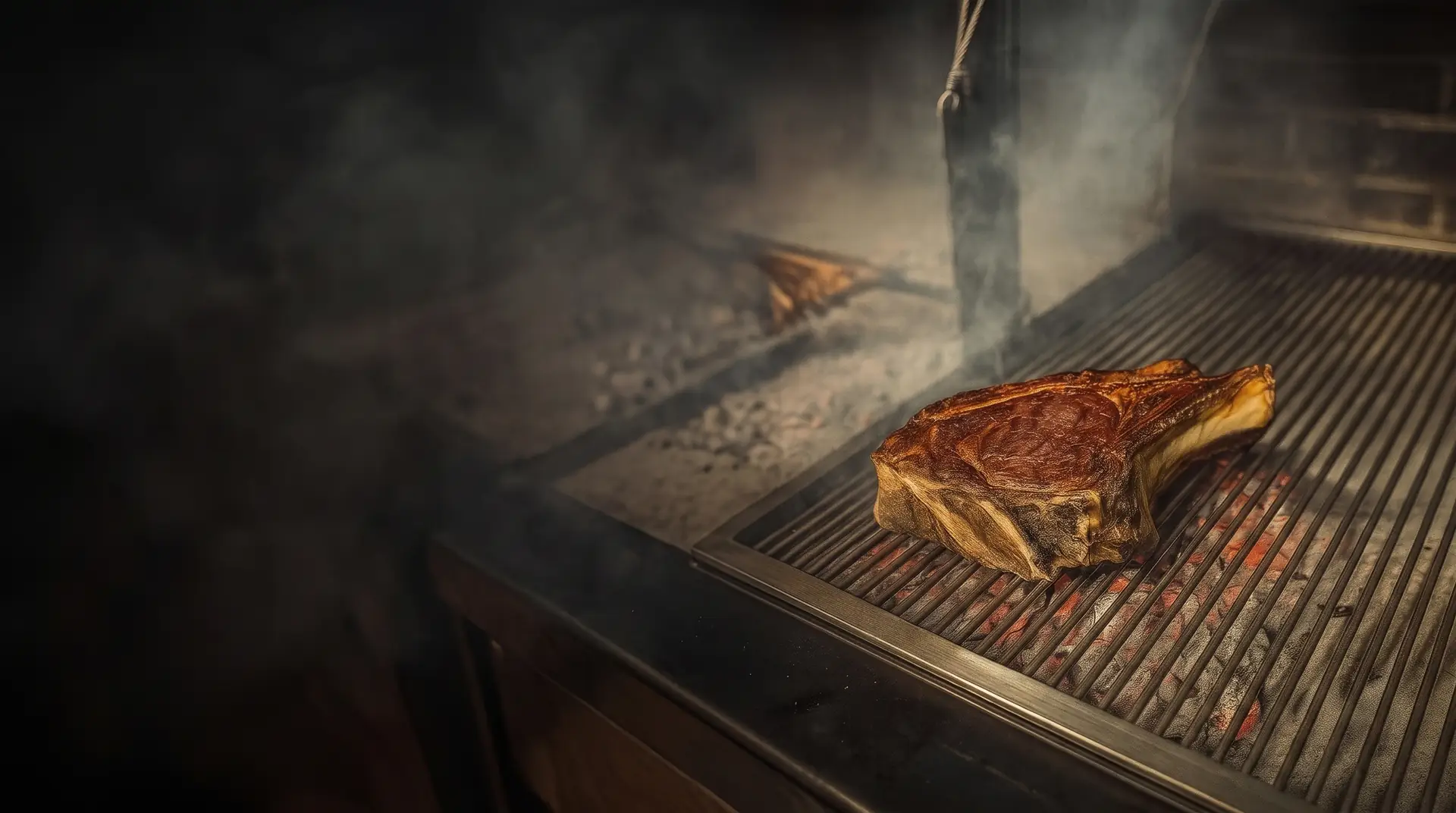 Chuletón con hueso sobre la parrilla de brasa, con humo y hierro ennegrecido